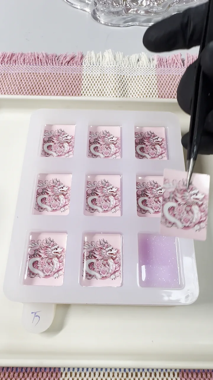 Maker placing pink dragon artwork into individual resin American Mahjong tile molds