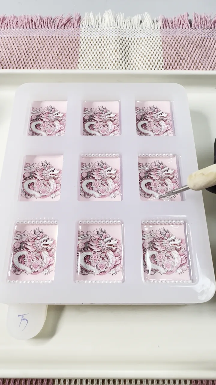 Maker placing pearl details one by one on pink dragon resin American Mahjong tile backs